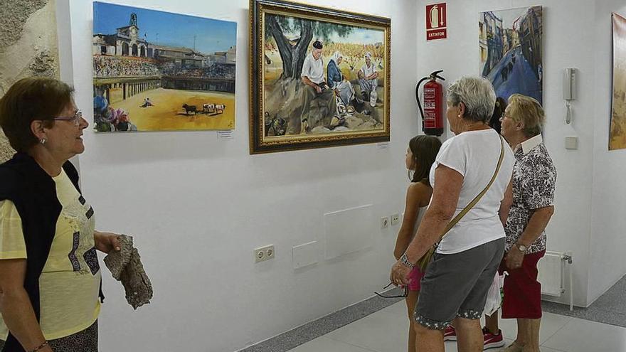 Un grupo de personas contempla cuadros artísticos ceñidos a actividades y festejos de Fermoselle.