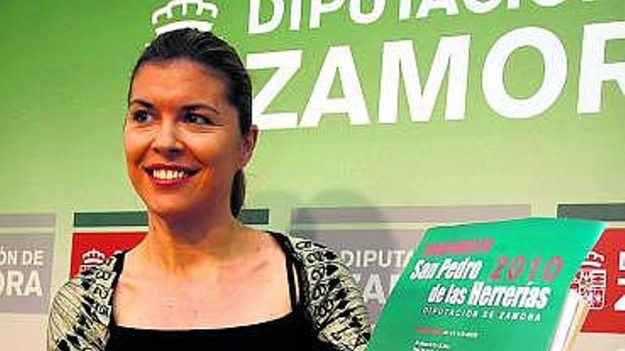 La diputada Clara San Damián muestra el cartel de los nuevos campamentos.