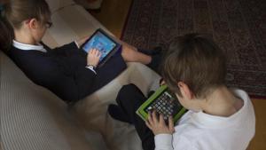 Dos niños de 7 y 10 años juegan con una tablet.