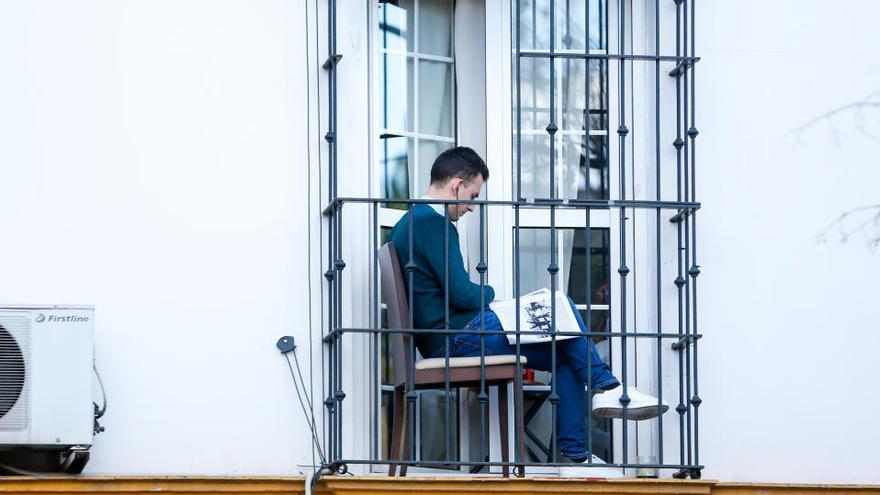 Un hombre lee en un balcón durante el confinamiento de la primera ola