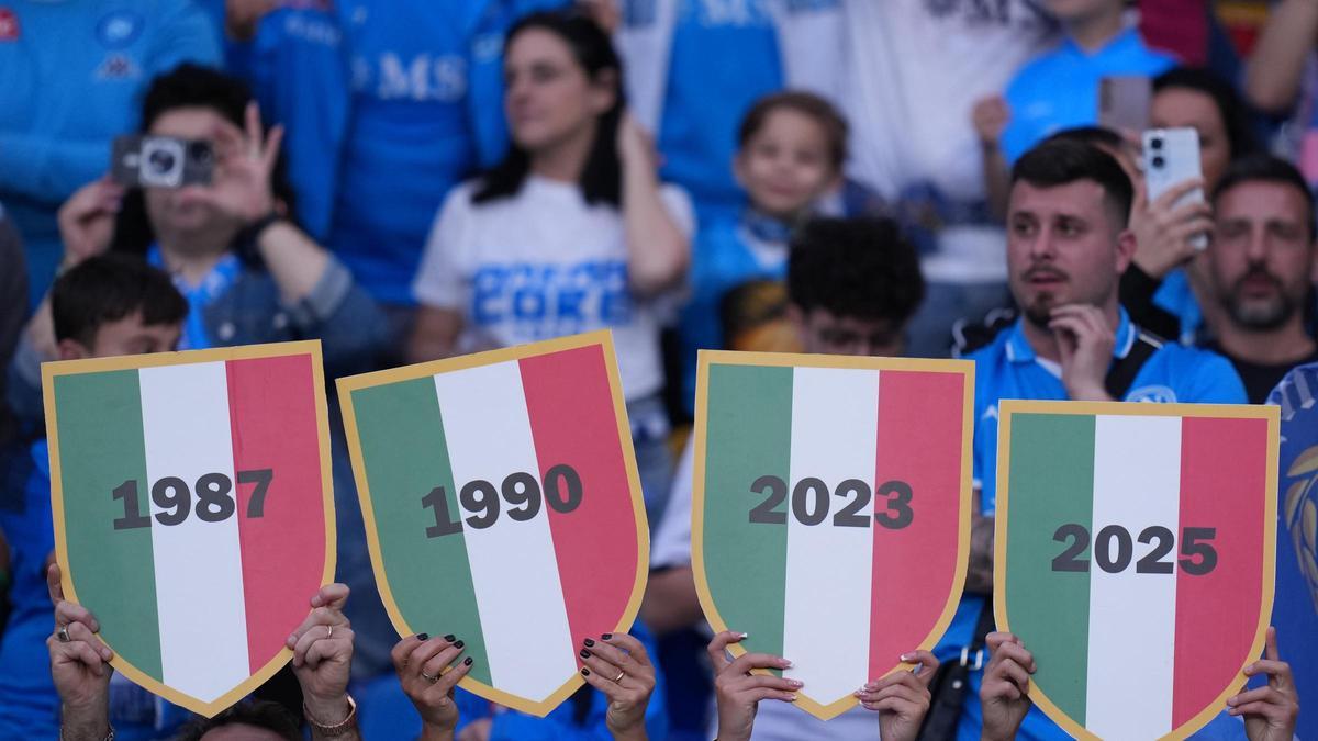 Aficionados del Nápoles exhiben pancartas con los cuatro títulos de su equipo en la Serie A.