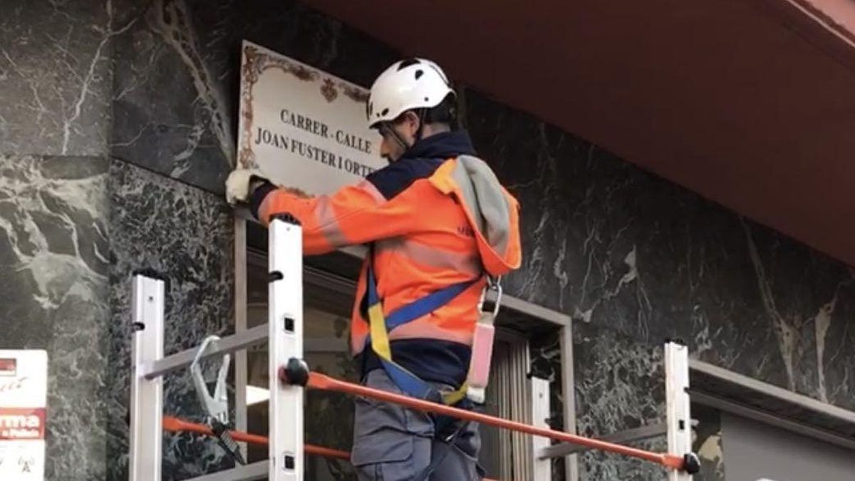 Un operario coloca la placa con el nombre de la calle Joan Fuster.