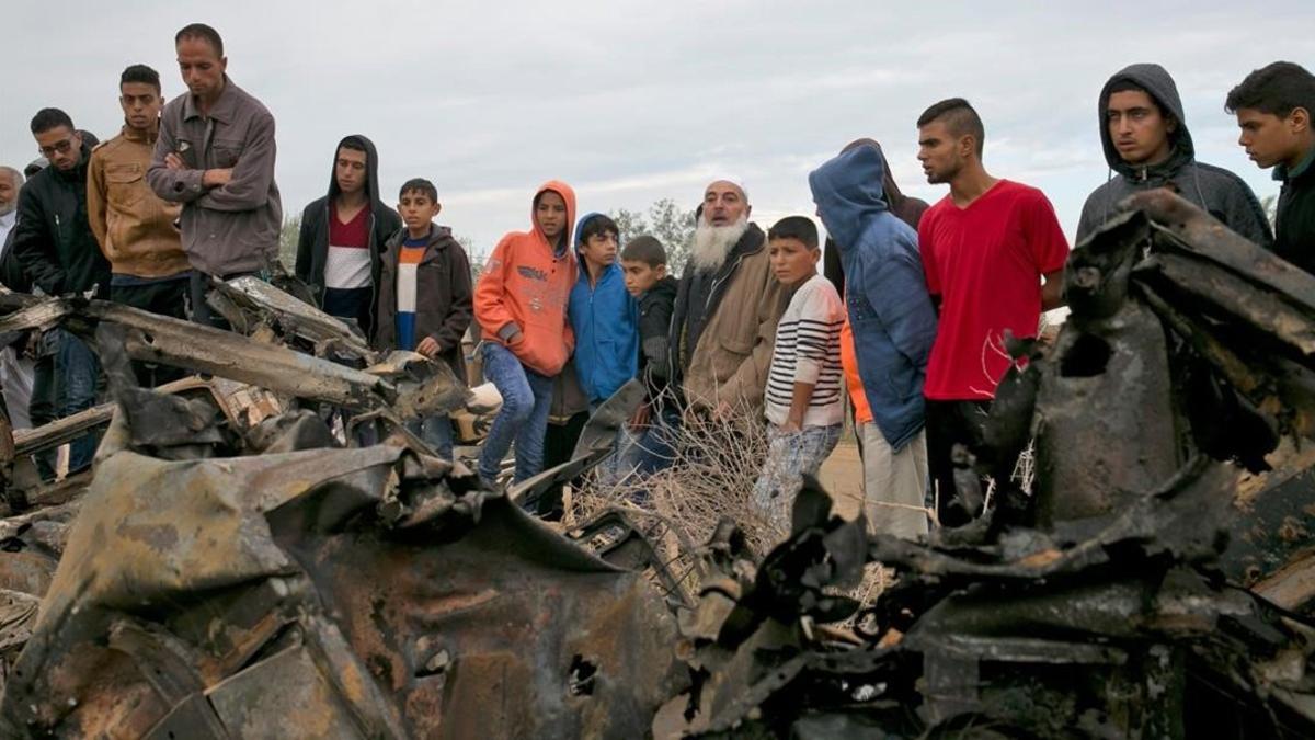 Unos palestinos permanecen junto a los restos de un automóvil destruido tras un ataque aéreo israelí en Khan Yunis, en el sur de la Franja de Gaza.