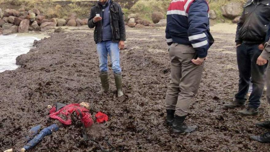 Vecinos y miembros de los servicios de emergencia tras recoger uno de los cadáveres. // Efe