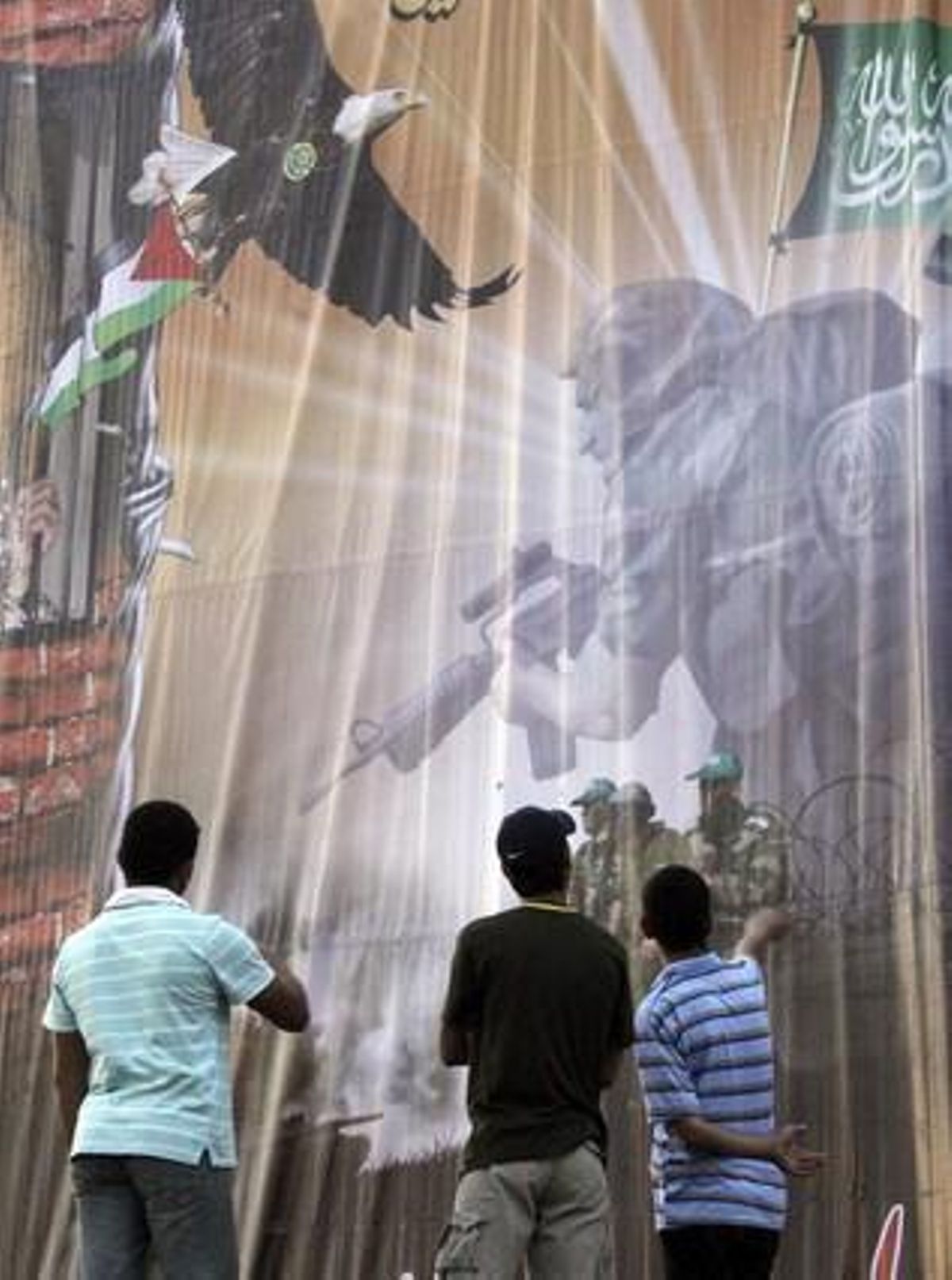 Palestins observen un gran cartell que dóna la benvinguda als pròxims presos palestins alliberats per Israel, a Gaza.