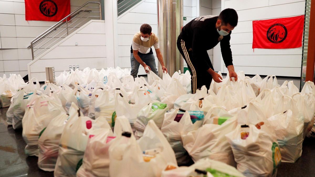 Dos integrantes de la plataforma integrada por organizaciones sociales &quot;Esperanza Obrera&quot; preparan las bolsas de comida