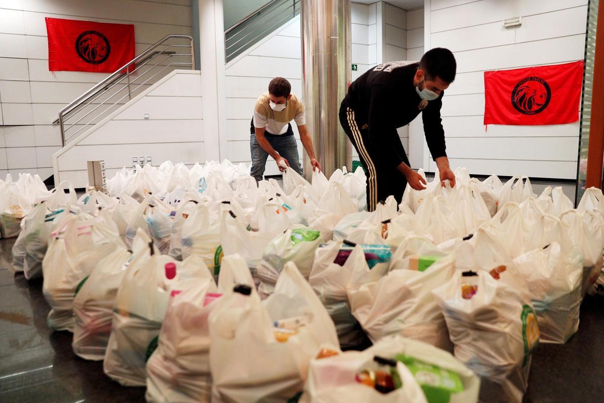 Dos integrantes de la plataforma integrada por organizaciones sociales "Esperanza Obrera" preparan las bolsas de comida