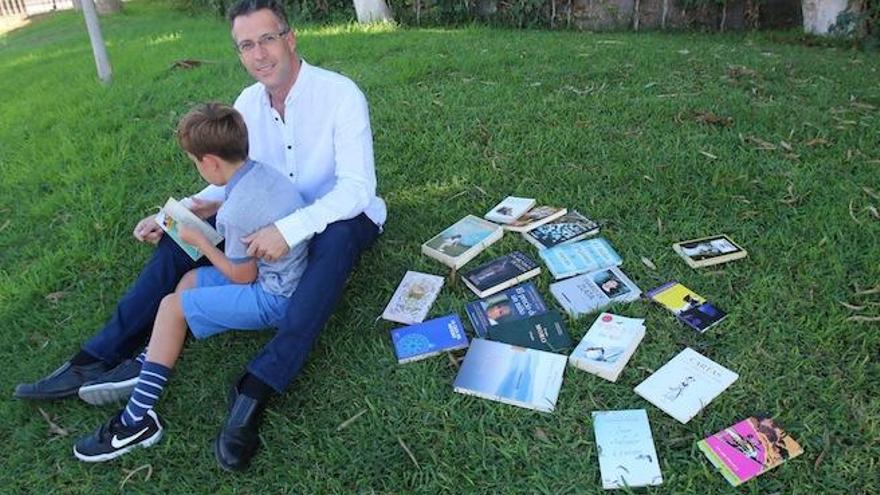 Vicente Moros, administrador del grupo Cazadores de libros Málaga, en Facebook, con su hijo Mario, rodeados de libros en el Parque del Oeste