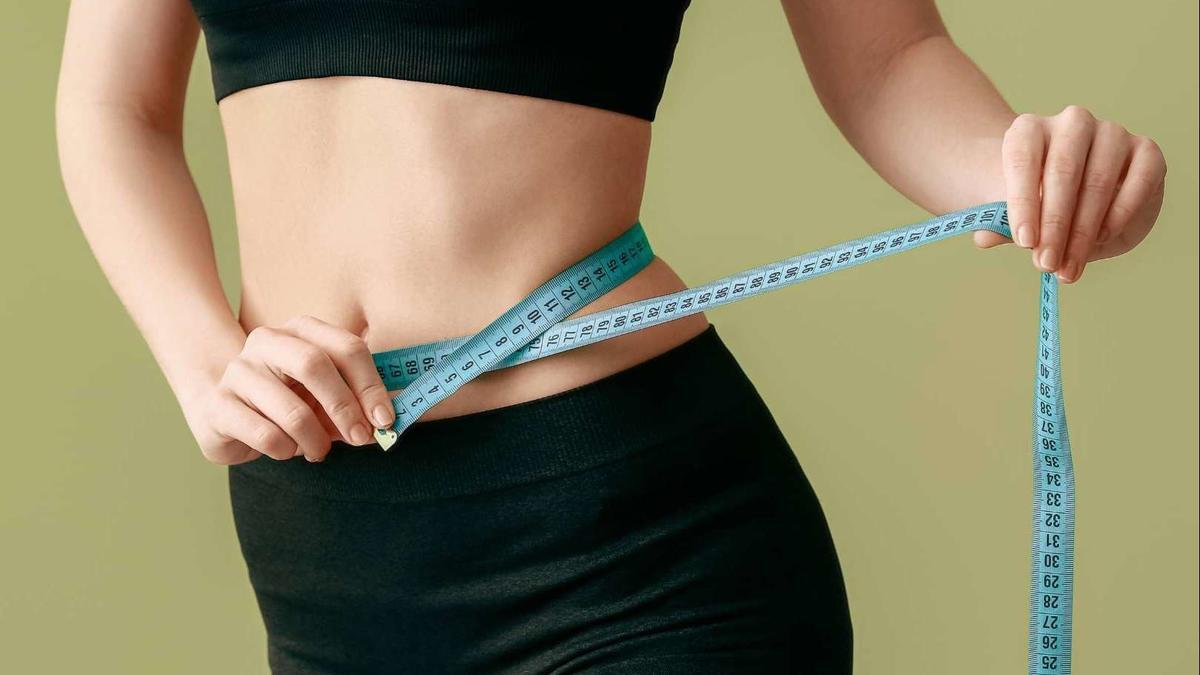 Una mujer mide el contorno de su cintura