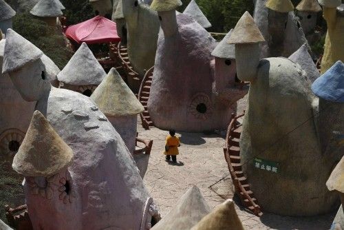 A dwarf walks in between mushroom-shaped houses after performances at Kunming World Butterflies Garden, Yunnan province
