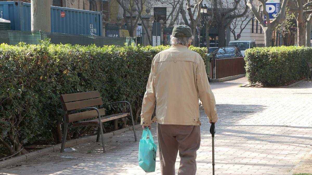 Un anciano, con una bolsa de la compra en el centro de Zaragoza.