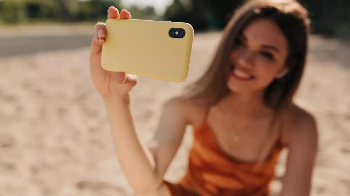 Una mujer se toma una foto con su móvil, cubierto con funda