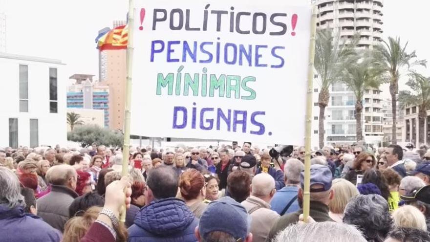 Un jubilado sostiene una pancarta ante cientos de personas en la protesta de Benidorm