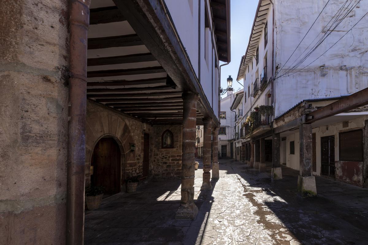 n callejón estrecho con un edificio de piedra a la izquierda y un edificio blanco a la derecha.