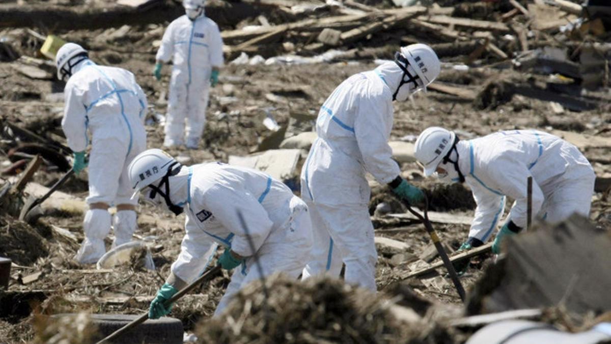 Miembros de la policía con trajes especiales inspeccionan terrenos arrasados en Minamisoma, en el departamento de Fukushima.