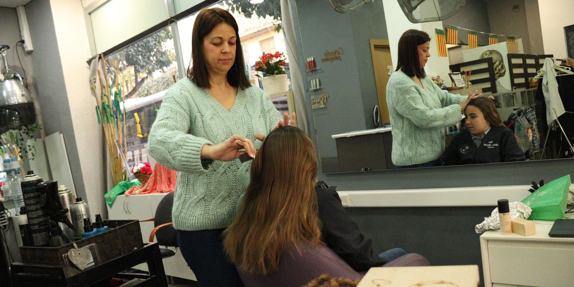 Eugenia Archilés Estrada peinando a la reina infantil, Vega Torrejón, en el local de Peluqueros Estrada.