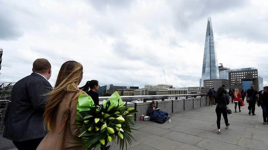 Una mujer atraviesa con un ramo de flores el Puente de Londres.