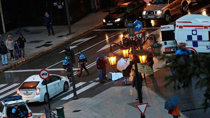 La mujer atropellada, en el suelo, junto a la ambulancia y el taxi implicado.