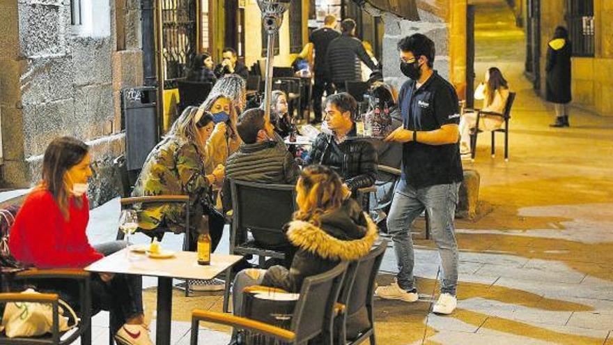 Un grupo de personas, al anochecer, en la terraza de un bar.