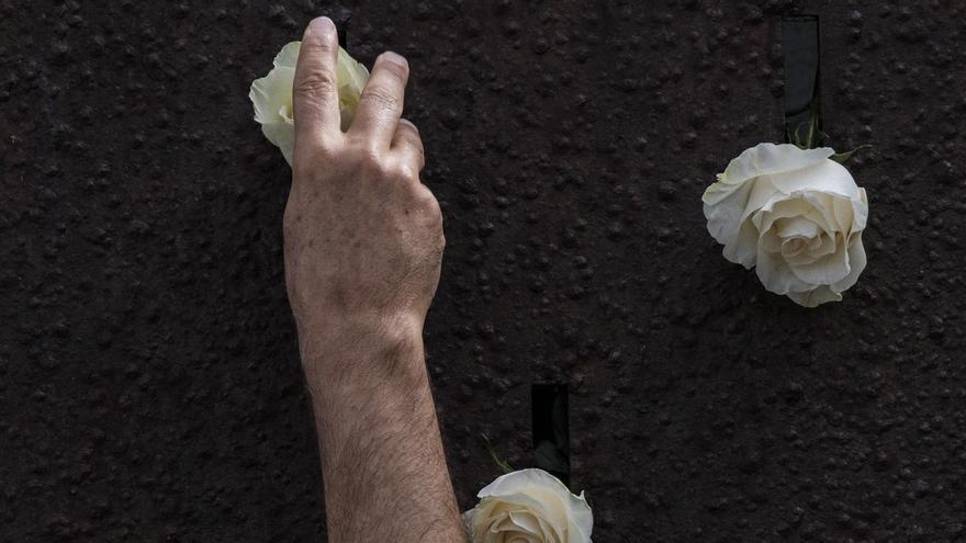 Un familiar de las víctimas del JK5022 coloca una flor en El Cubo, en La Puntilla.