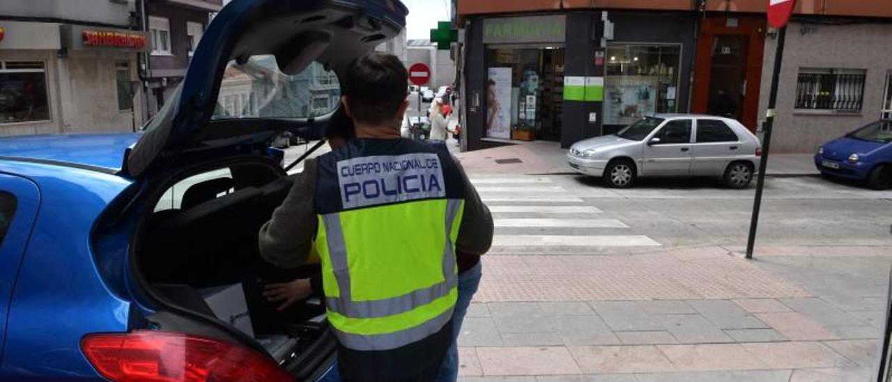 Un agente, junto a un vehículo policial, frente al edificio en el que ocurrió la agresión.