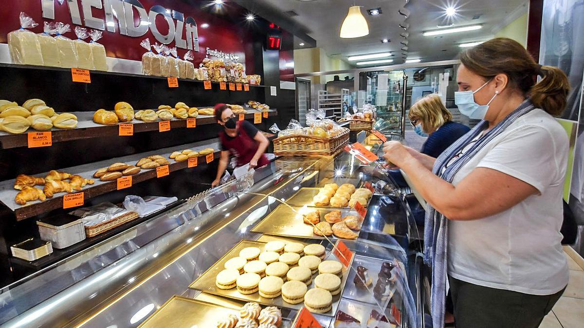 Una empleada de las panaderías Mendoza atiende a dos clientas. | | JUAN CASTRO