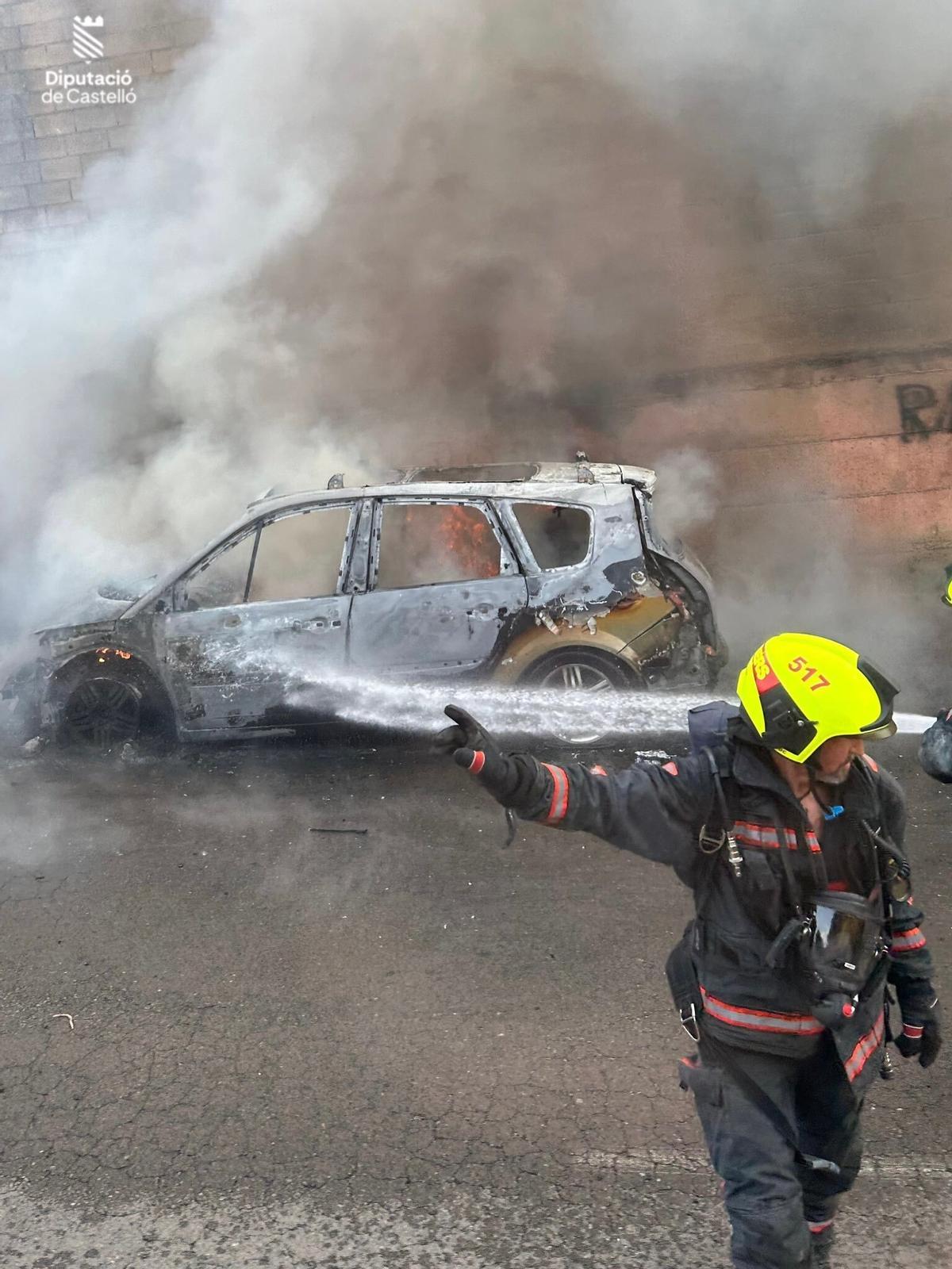Los bomberos echan agua sobre el coche en llamas.
