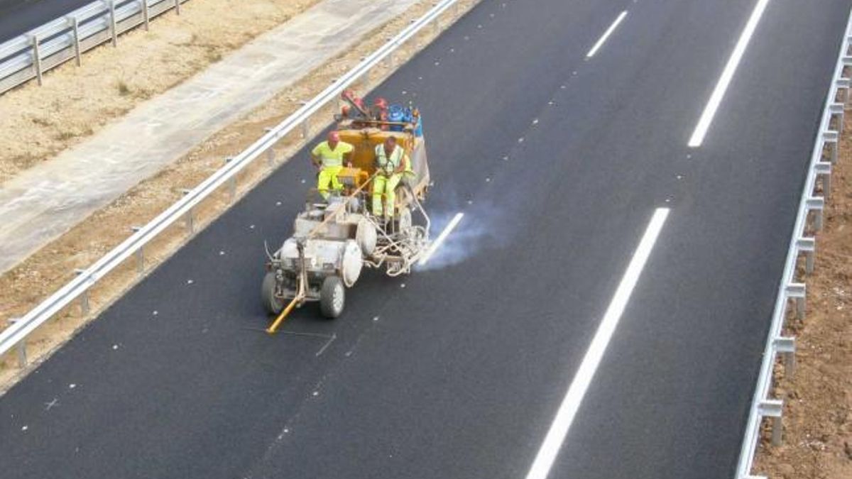Varios operarios, pintando la señalización en una autovía.