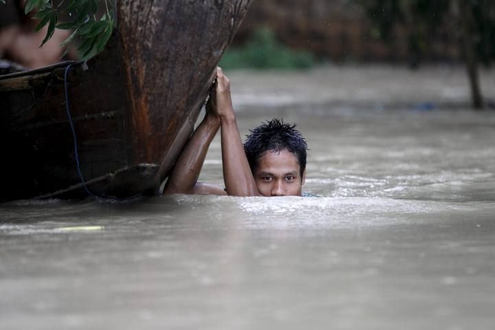 A boy moves his boat in a flooded village outside Zalun Township, Irrawaddy Delta