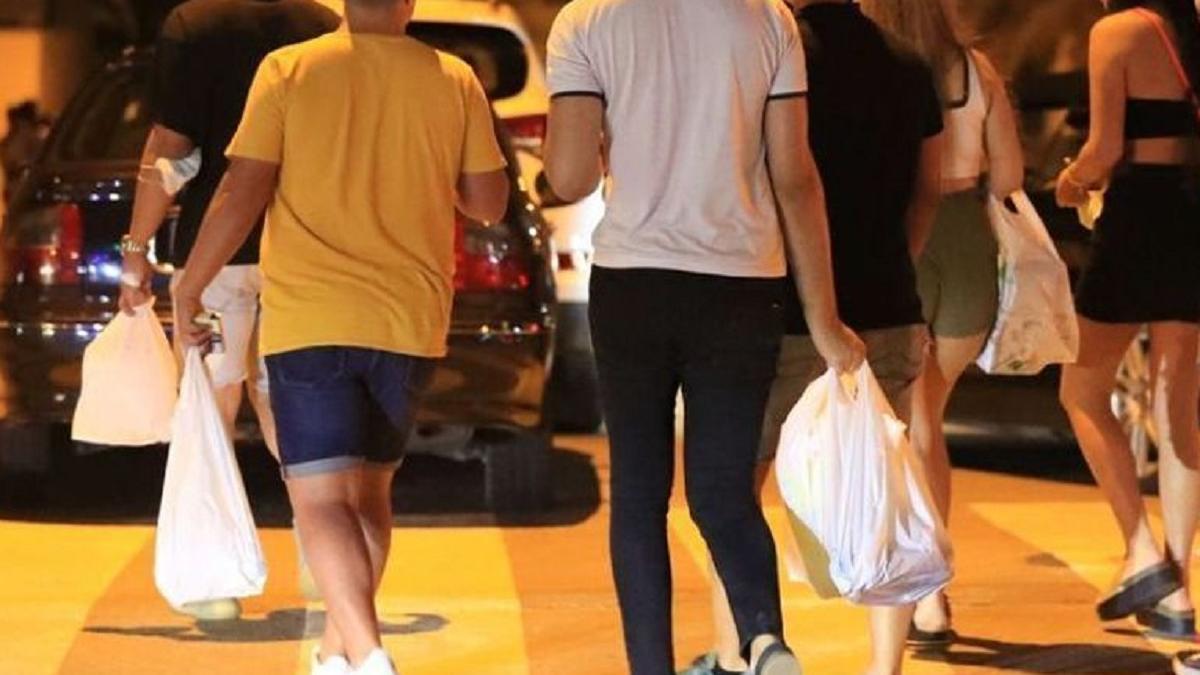 Jóvenes con bolsas de bebidas para hacer botellón.