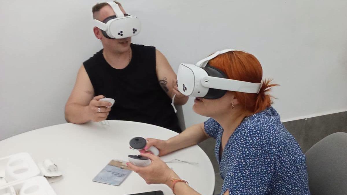 Dos turistas prueban las gafas de realidad virtual en la Oficina de Turismo de Salas.