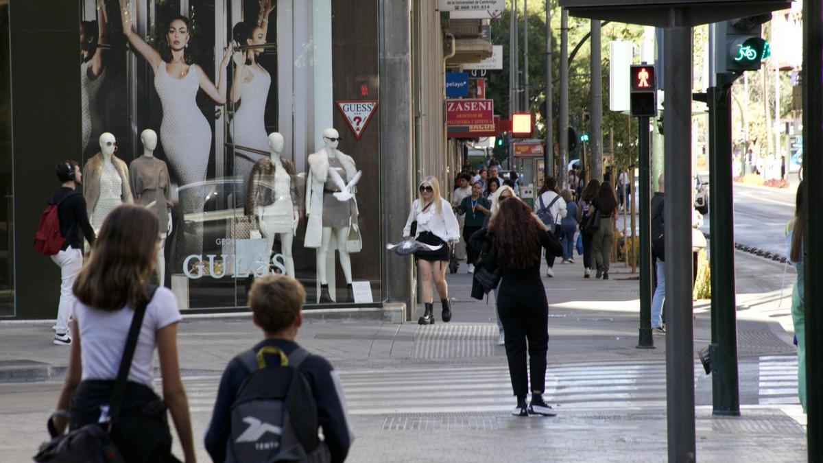 Abrigos en un escaparate de la plaza Fuensanta de Murcia frente a un termómetro que marcaba 25º.