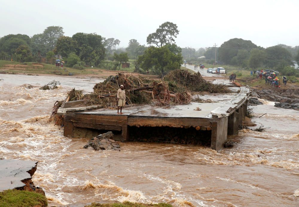 A man looks at a washed away bridge along ...