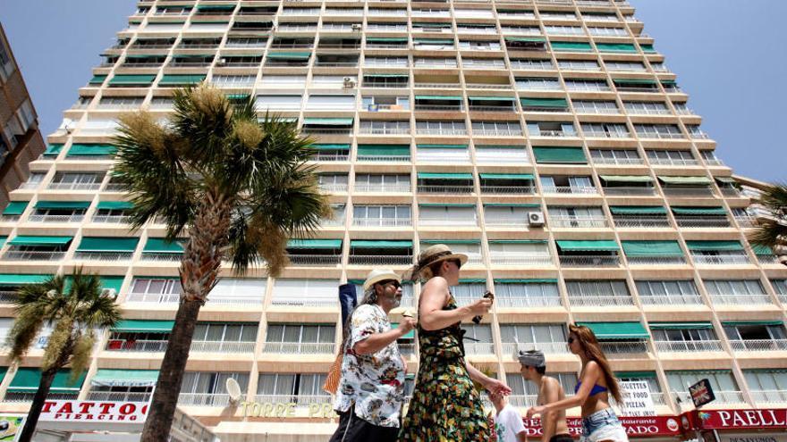 Un grupo de turistas pasa junto a un edificio de apartamentos turísticos en Benidorm.