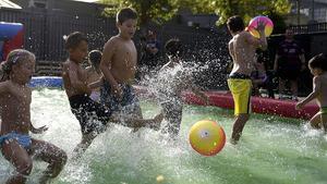 Un grupo de niños juegan al fútbol en una piscina inflable.