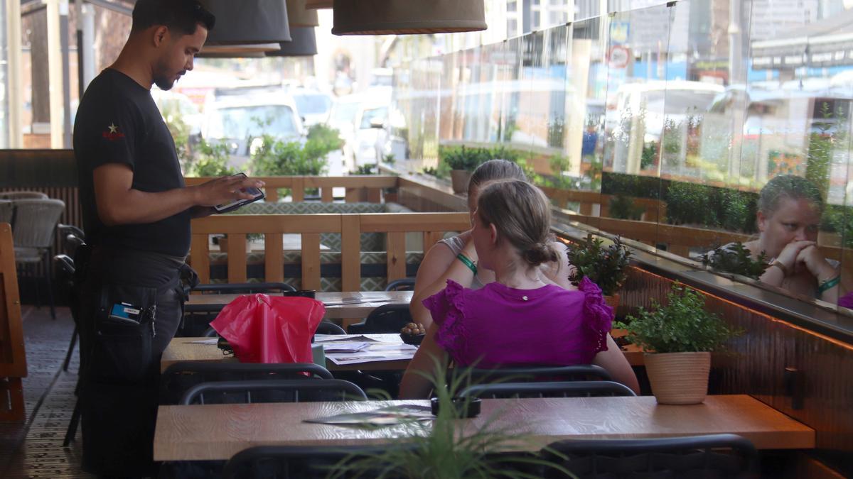 Un cambrer pren nota a dues turistes en una terrassa de Platja d'Aro
