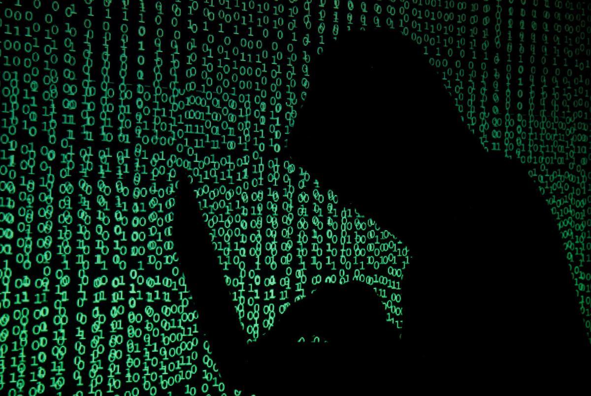 A hooded man holds a laptop computer as cyber code is projected on him in this illustration picture taken on May 13, 2017. Capitalizing on spying tools believed to have been developed by the U.S. National Security Agency, hackers staged a cyber assault with a self-spreading malware that has infected tens of thousands of computers in nearly 100 countries. REUTERS/Kacper Pempel/Illustration
