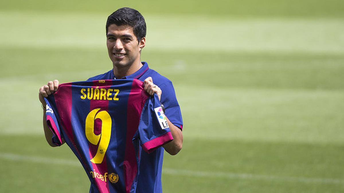 Luis Suárez posa con la camiseta del Camp Nou sobre el césped del Camp Nou, este martes, día de su presentación
