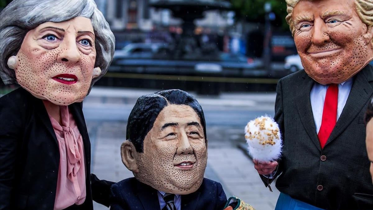 Tres activistas con las caretas de Trump, Theresa May y Shinzo Abe, en Canadá.