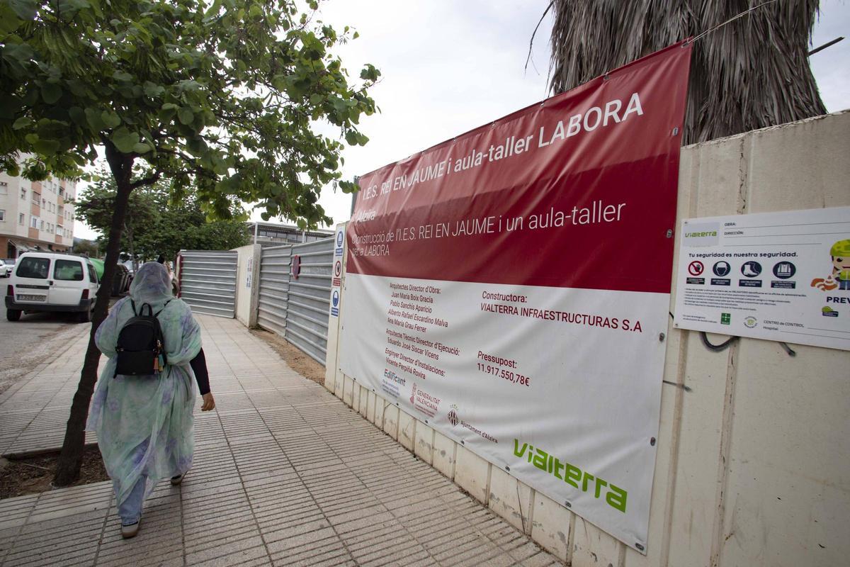 Una mujer pasea frente las obras del inacabado instituto Rei En Jaume d'Alzira.