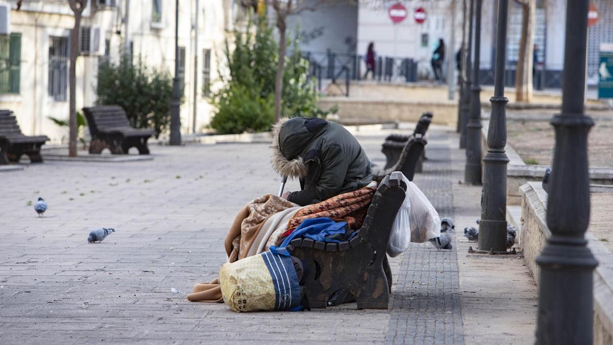 Una persona sin techo en un banco del barrio del Carmen de Xàtiva.