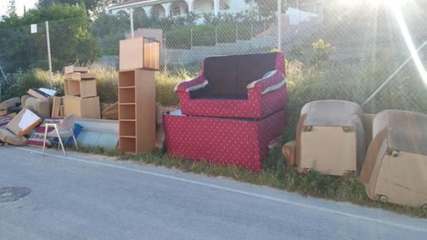 Una hilera de muebles abandonados junto a un contenedor de basura en la calle Algarrobo.