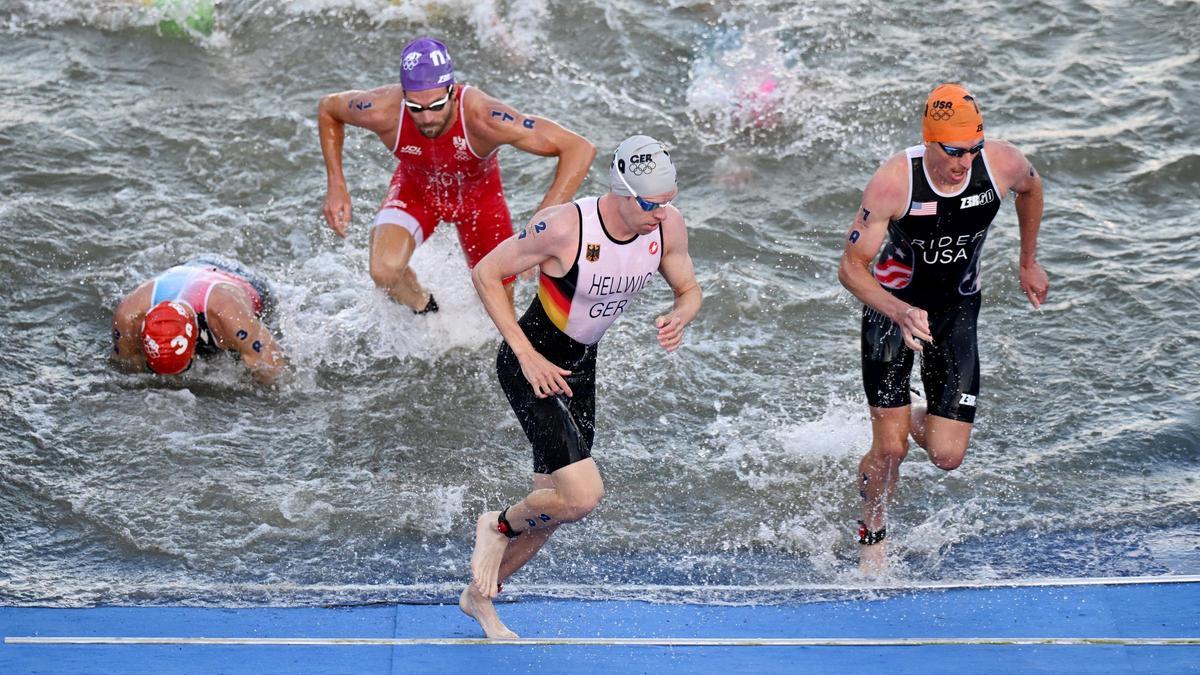 El alemán Tim Hellwig (2.º por la derecha) sale del agua del Sena durante la etapa de natación del triatlón mixto en el Puente Alexandre III.