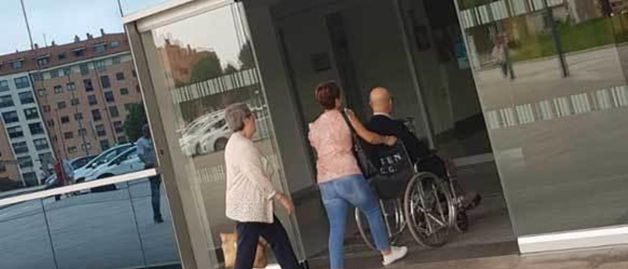 Un paciente en una silla de ruedas del hospital y dos acompañantes entrando ayer en Consultas Externas.