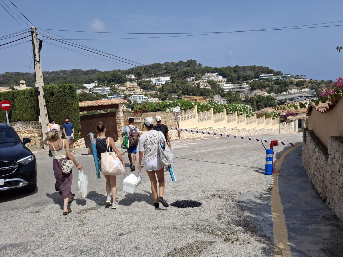 Bañistas al llegar a la barrera de la cala de la Barraca