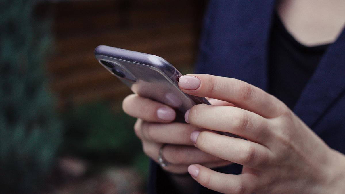 Una mujer mira su móvil.