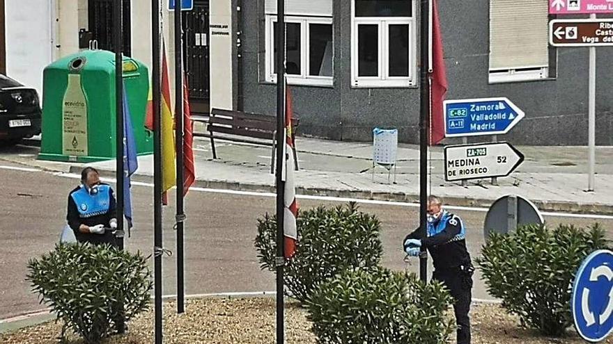 Dos policías cambian la posición de las banderas de una rotonda.