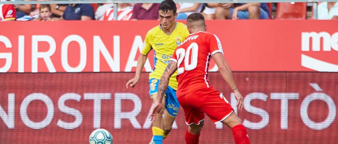 Pedri completa un pase en el estadio de Montilivi con la presión de Maffeo.