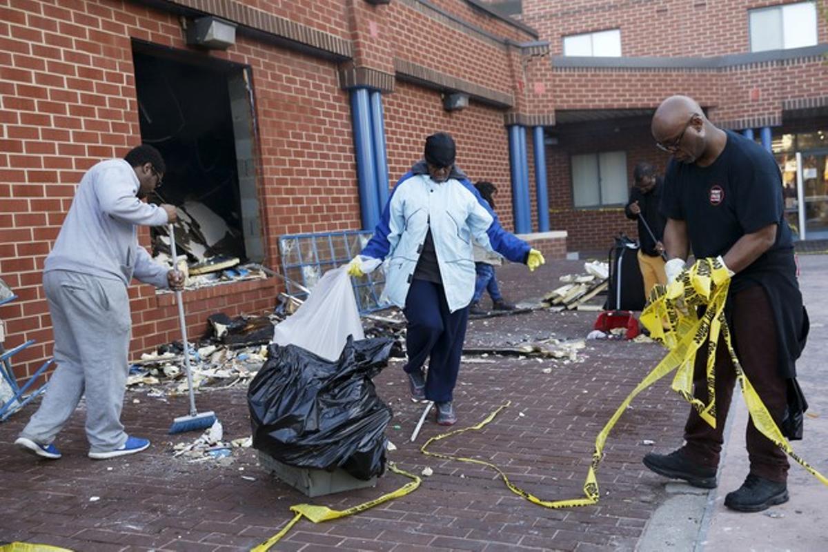 Vecinos de Baltimore limpian una calle de los restos de los disturbios.