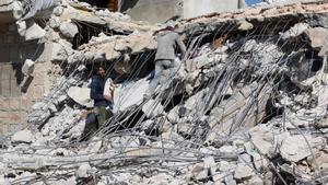 Dos hombres trabajan entre los escombros de un edificio derrumbado por el terremoto en la población siria de Atarib, en Alepo, en territorio bajo control opositor.